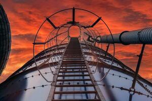 mirando arriba un silo escalera a un brillante naranja cielo foto