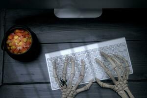 esqueleto manos en un teclado en un negro escritorio foto