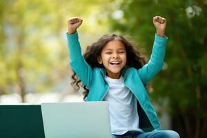 un joven contento niña utilizando un ordenador portátil en el habitación con su brazo arriba foto