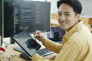 joven programador trabajando en escritorio ordenador personal en oficina de software compañía. foto