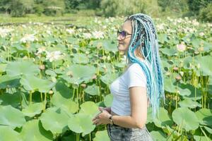 joven mujer con hermosa azul rastas descansando en loto lago foto