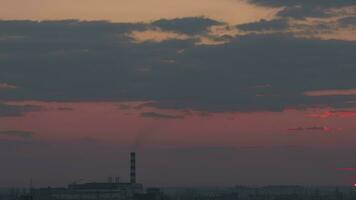 lasso di tempo, crepuscolo nel un industriale città. nuvole nel il cielo e rosso tramonto video