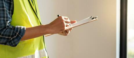 el inspector o ingeniero está inspeccionando la construcción y el aseguramiento de la calidad de la nueva casa usando una lista de verificación. ingenieros o arquitectos o contratistas trabajan para construir la casa antes de entregársela al propietario foto