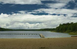 summer landscape with a lake, trees, blue sky and clouds on a warm day photo