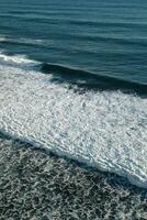 Amazing view of the blue ocean with white foam and waves. Beauty of nature. Top view. Vertical photo