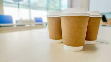 Tres tazas de caliente café con papel tazas en mesa foto