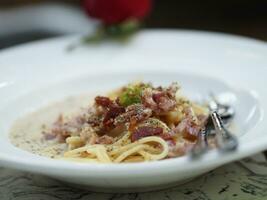 espaguetis carbonara con no fumado tocino, panceta, guanciale pesado crema, espaguetis alla carbonara comida en blanco plato en el mesa foto