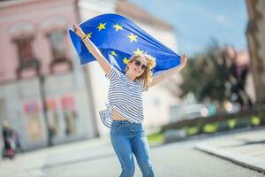 atractivo contento joven niña con el bandera de el europeo Unión foto