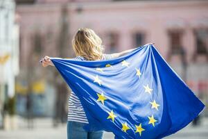 atractivo contento joven niña con el bandera de el europeo Unión foto