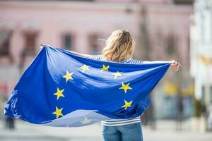 atractivo contento joven niña con el bandera de el europeo Unión foto