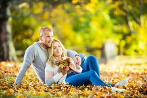 A loving couple in an autumn park lies on the leaves photo