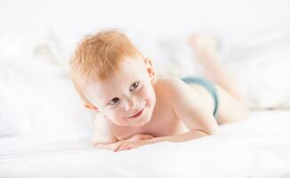 Habby young smilling child boy in white bed photo