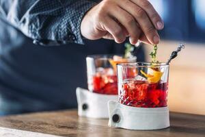 Bartender precisely preparing  cocktail drink with fruit and herb decoration. Bartender only hands preparing alcoholic non-alcoholic drink photo