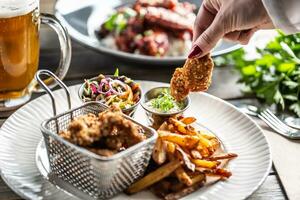 Crispy breaded chicken nuggets with french fries served on a plate with a dip and a salad photo