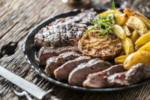 Grilled beef Rib Eye steak with garlic american potatoes rosemary salt and spices photo