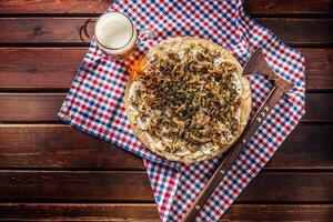 Traditional slovak potato pancake with fried onion bacon and cheese bryndza with draft beer photo