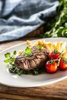 Cooked sirloin beef steak served with vegetables on a plate photo