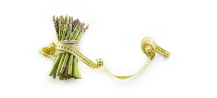 Fresh green asparagus with measure tape isolated on white background photo