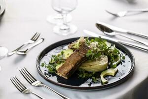 lujoso mesa ajuste con un oscuro plato lleno de vegetariano ensalada con marinado tofu foto
