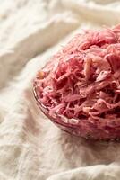 Sour cabbage served in a glass bowl on a rustic tablecloth photo