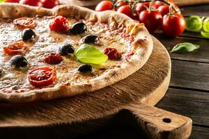 Homemade pizza with tomatoes mozzarella cheese olives and basil photo