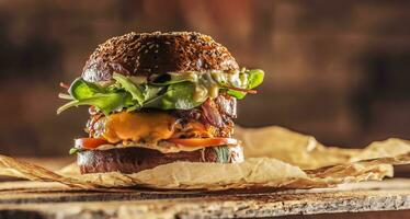 Home made tasty burger with bacon onion cheese ane lettuce on wooden box photo