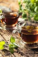 A cup of melissa tea with herbs on wooden table photo