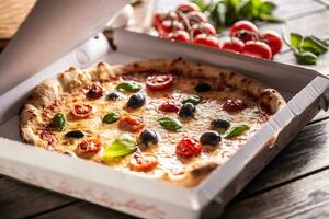 Pizza in a cardboard box on table ready to customer. photo