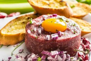 Beef tartare with egg yolk red onion chili peppers herbs and bruschetta photo