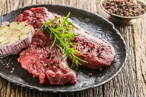 Beef meeat Rib-Eye steak wit rosemary salt and pepper on black plate photo