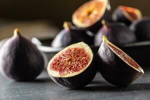 A few figs in a black bowl on an dark concrete table photo