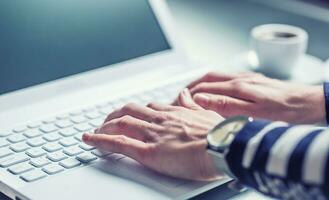 Woman hands typing on the keyboard of laptop, close-up of online working. photo