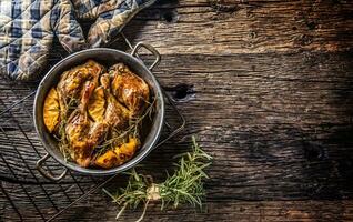 Roasted duck legs in pan with oranges herbs red cabbage and potato pankaces photo