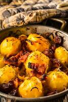 Potatoes. Roasted potatoes with bacon onion and sausages on old oak table photo