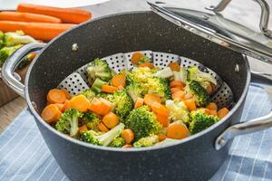 Steamed mixed vegetable in black pot. Healthy vegetable concept photo