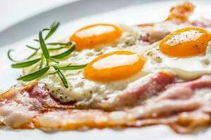 Ham and Eggs. Bacon and Eggs. Salted egg with pepper on white plate. English breakfast photo