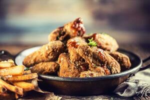 Fried chicken wings with fries on table in pub. photo