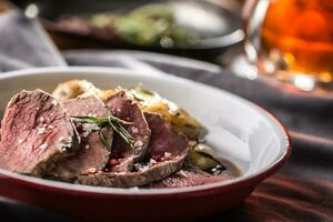 Sliced Beef tenderloin roasted steak potatoes rosemary and draft beer photo