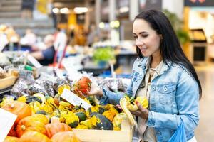 Smiling woman checks on pumpkins offered for sale in the grocery store photo