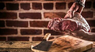 Butcher man hands holding raw beef steak in butchery. photo