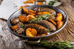 Sausages. Roasted pork sausage in a pan with potatoes and rosemary. photo