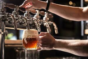 manos de el pub empleado tocando cerveza dentro un redondeado jarra foto