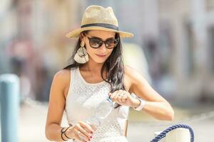 A beautiful woman opens a bottle of pure mineral water during a hot a summer day photo