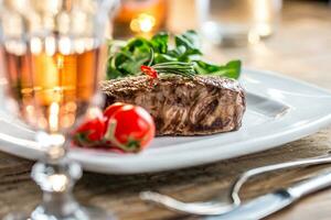 Beef Steak. Juicy beef steak. Gourmet steak with vegetables and glass of rose wine on wooden table photo