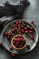 Metallic vintage tray, surface and cup with red juicy cherries inside the cup and scattered around the tray - Top Of view photo