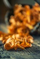 Raw chanterelles mushroom on wood scattered from a wooden wicker basket photo