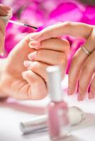 Manicure specialist painting woman gel nail. Art - French manicure photo