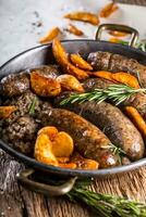 Sausages.Roasted pork sausage in a pan with potatoes and rosemary. photo