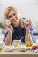 Happy woman takes garlic heads and makes them into preserves in the kitchen photo