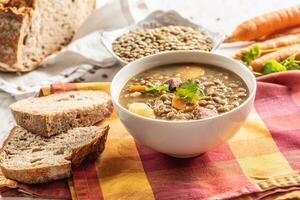 Lentil soup with pieces of smoked pork neck, carrots, potatoes and coriander photo